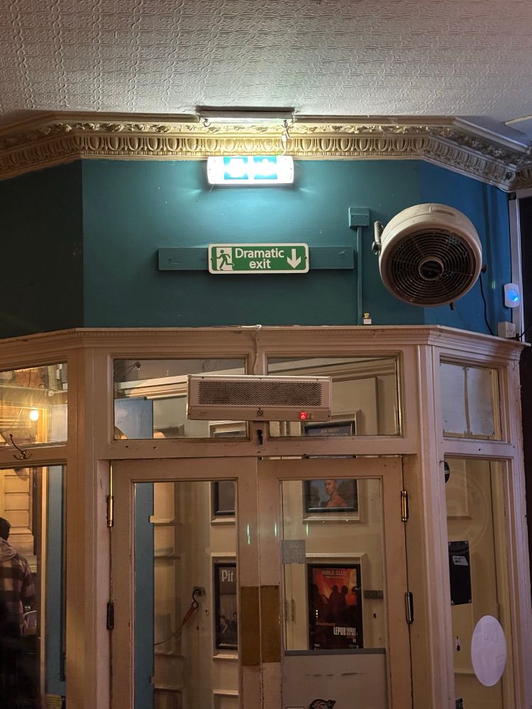 Fake emergency sign over the main door saying “ Dramatic Exit” 