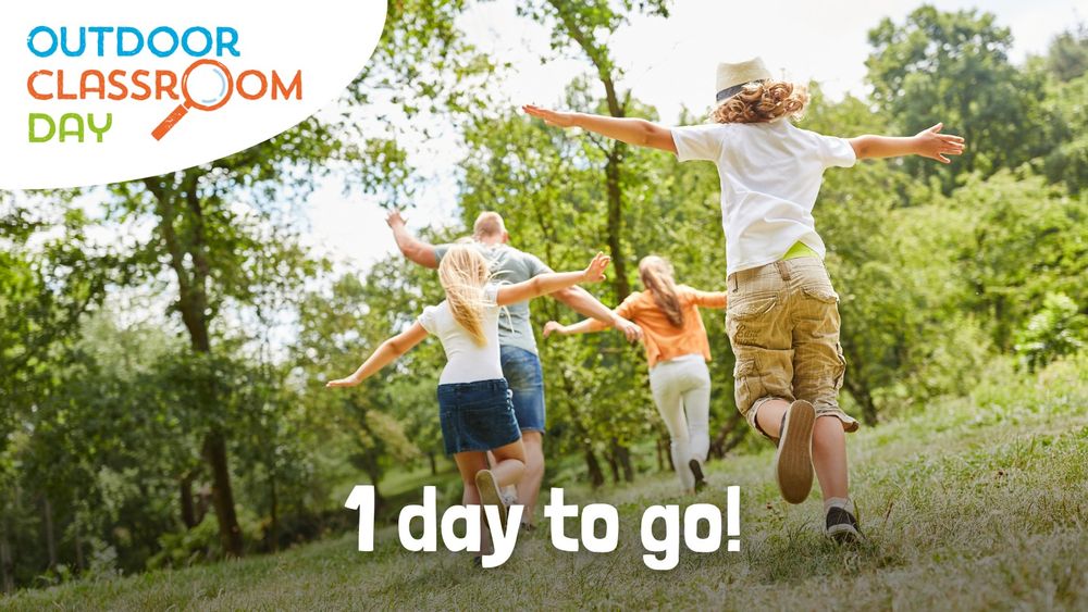 A graphic featuring an image of children running away from the camera into the trees with their arms spread wide. The words '1 day to go!' are written in white along the bottom of the image, and the Outdoor Classroom Day logo is overlaid in the top left corner.