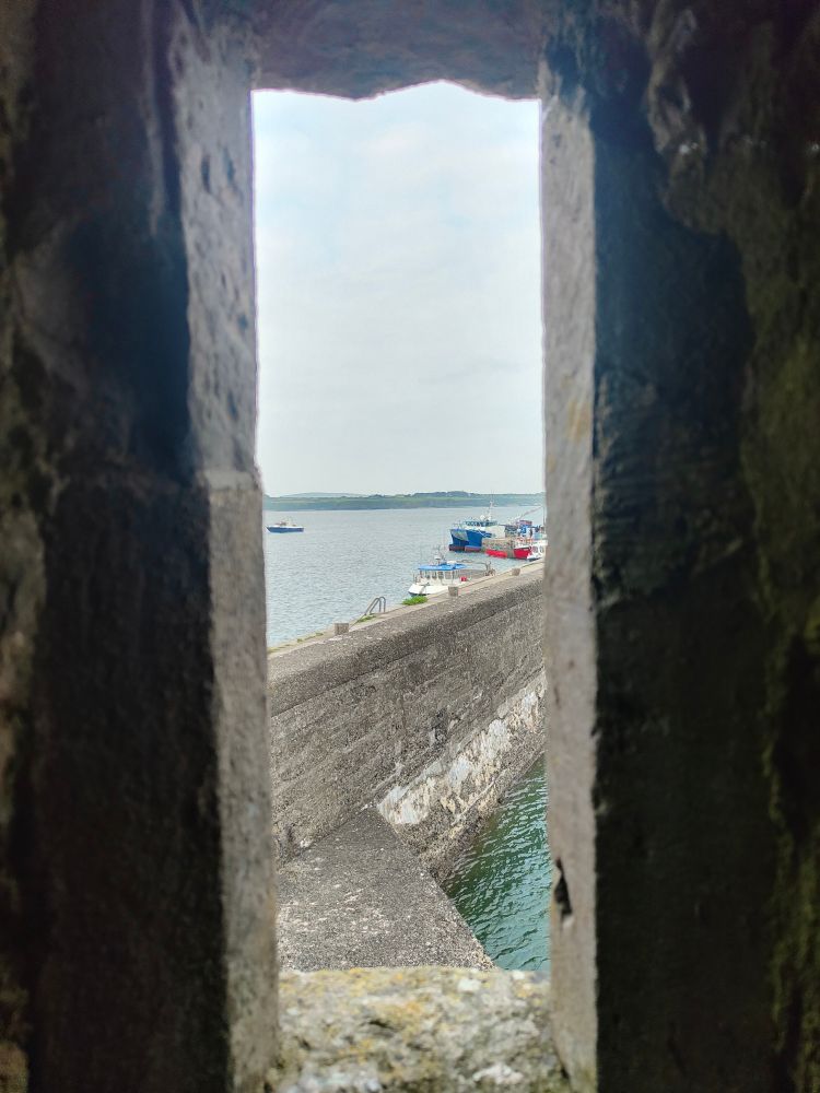 A photo taken from the lookout tower in  Carrigaholt Castle looking out over the Shannon Estuary. The pier can be seen in the foreground.