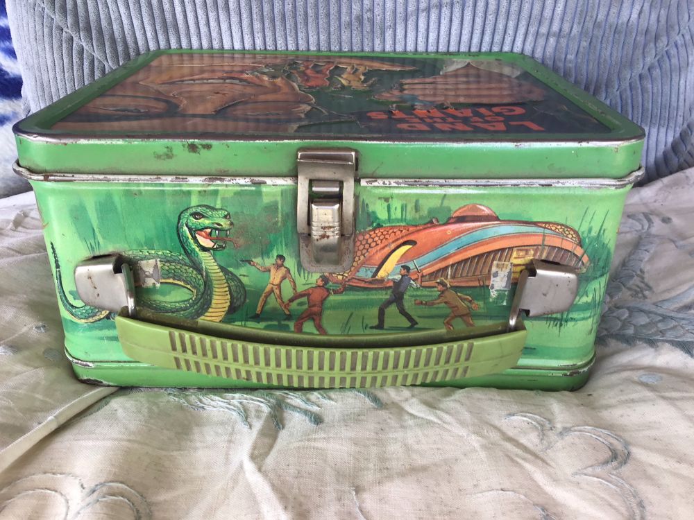 Handle side of box. A giant snake menaces tiny people in front of their spaceship.