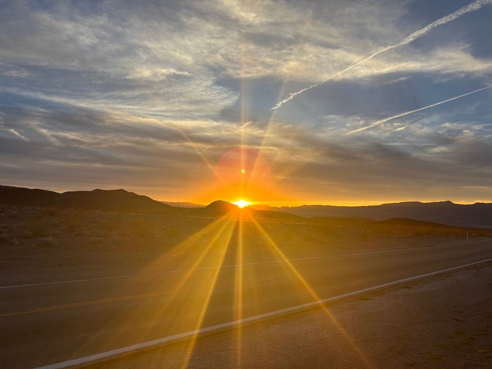 The sun setting over eldorado wilderness. The sun rays are BEAMING out over the desert and road as the sun begins to set. 