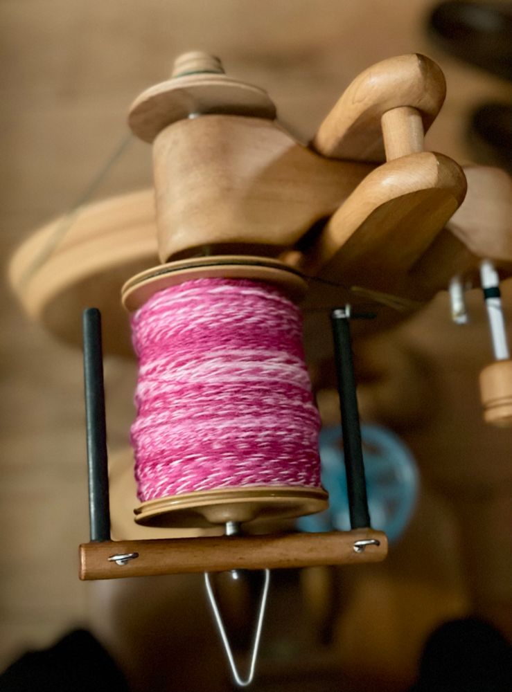 Shades of pink. Closeup of a bobbin filled with a two-ply yarn, about worsted weight. 