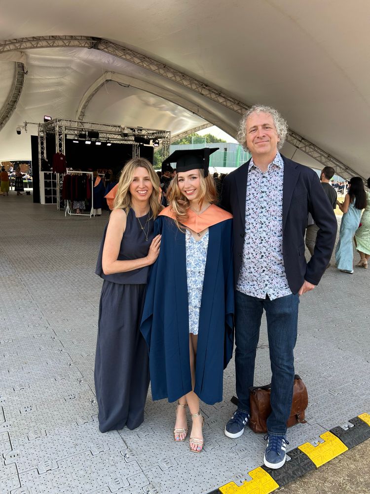 Mum and Tom stand either side of daughter Daisy in her graduation garb.