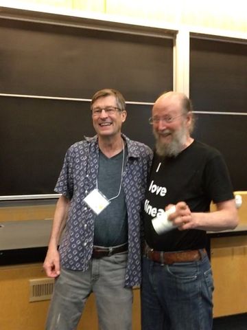 Image of (left) Andrew Barto and (right) Richard Sutton smiling while standing in front of a chalkboard