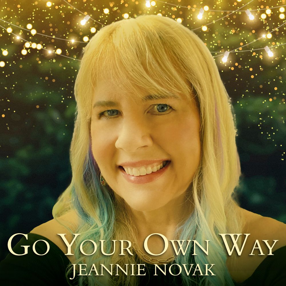 Cover image for “Go Your Own Way” single depicting photo of Jeannie Novak against a background of glowing lights and green foliage.
