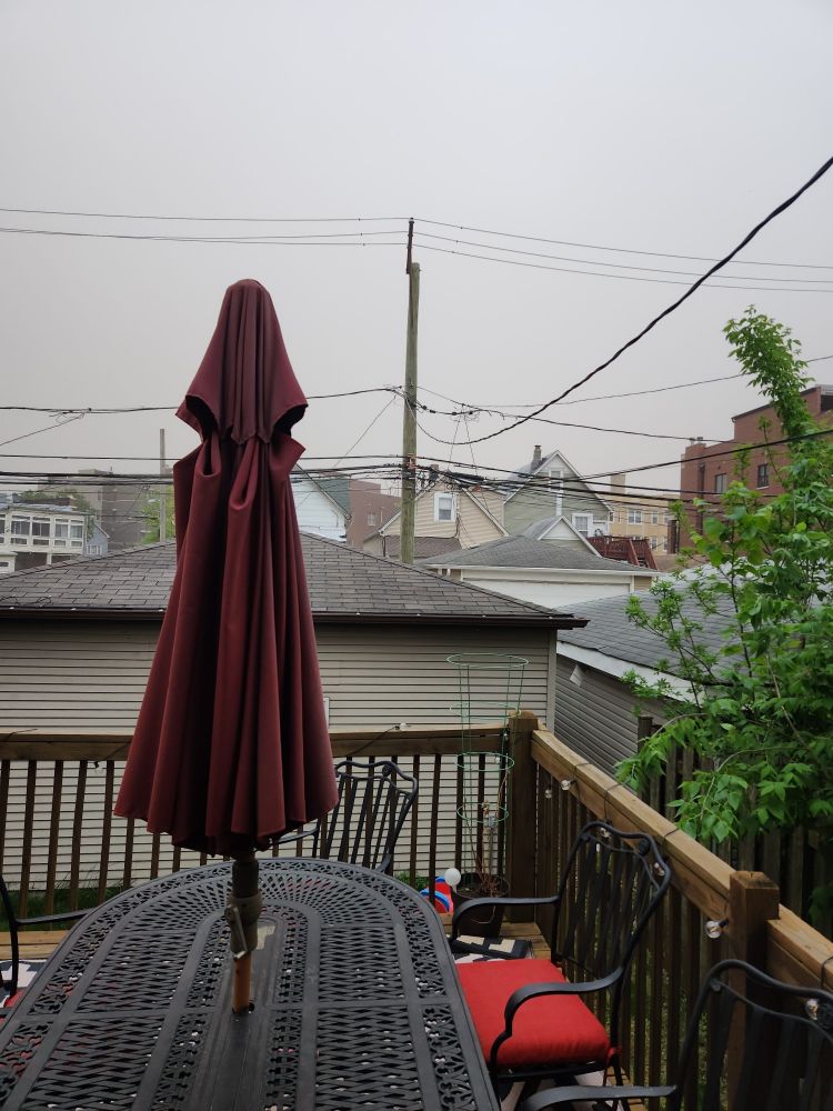 A patio set on a porch. The sky is dirty brown as a dust storm rolls through Chicago like it's the freaking Dust Bowl again.