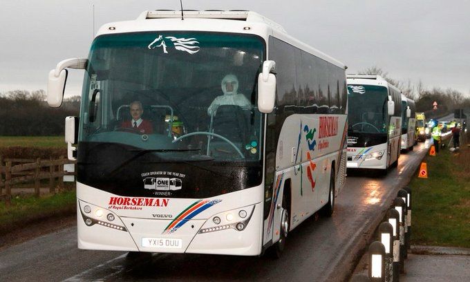 Picture of a coach convoy, with a HORSEMAN logo clearly visible. The driver wears a tie and jacket, behind him is a man in full hazmat gear.