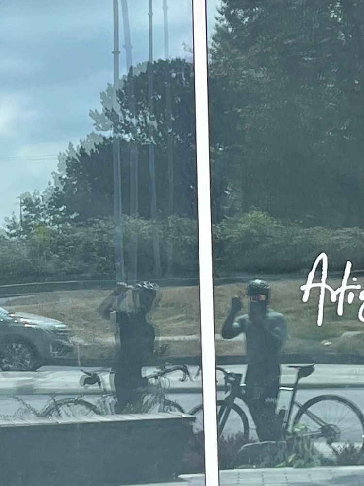 two cyclists reflected in window with their bikes