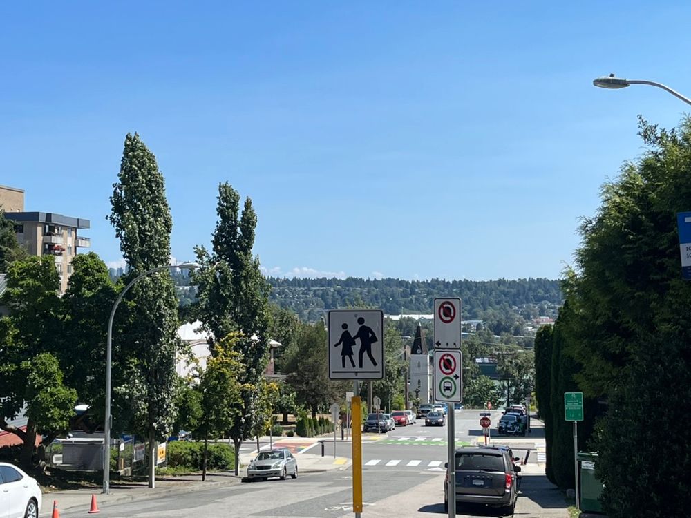 Street intersction with pedestrian crossing sign, traffic lights and hills ahead. Location: New West