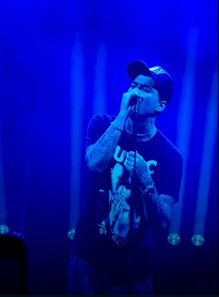 Zayn at his tour singing in blue light