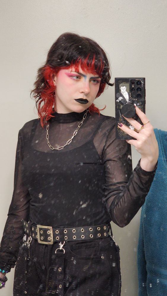 Same person showing a mesh top, silver necklace and black grommet belt.