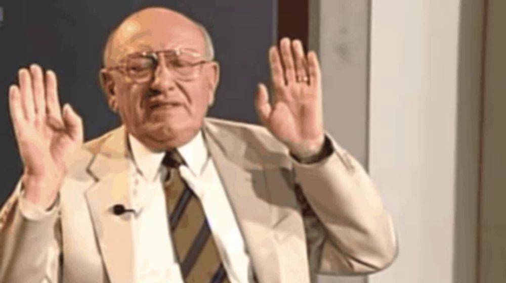 an older man in a suit and tie is raising his hands