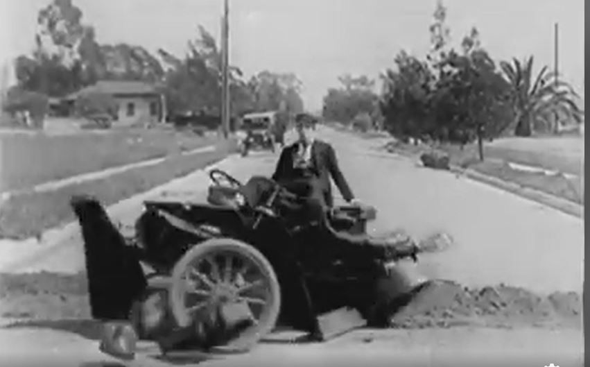 Buster Keaton rikkoutuvan auton ohjaimissa.