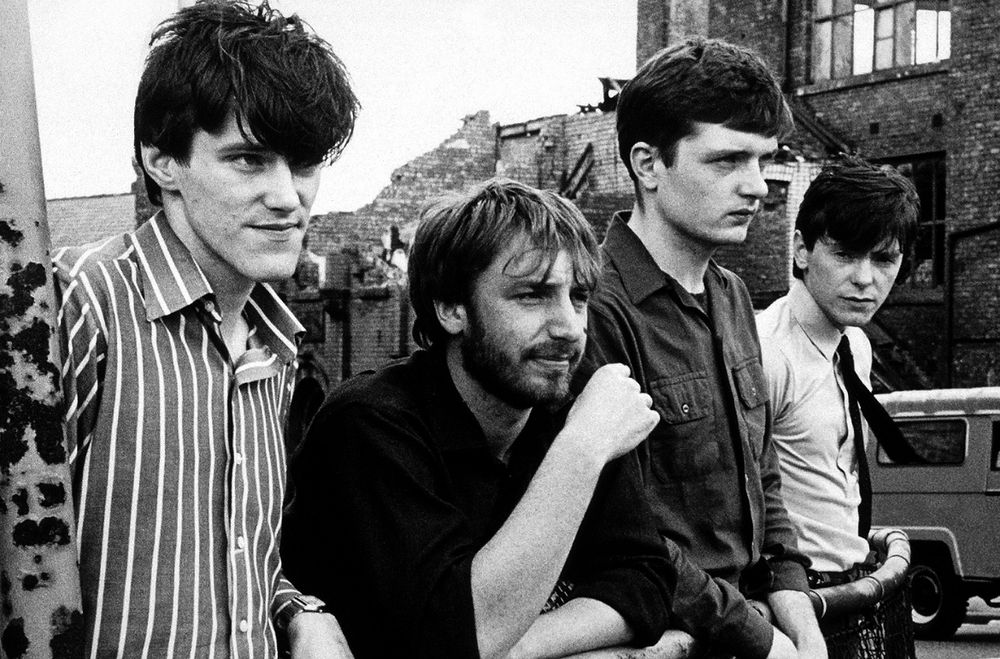 Stephen Morris, Peter Hook, Ian Curtis, and Bernard Sumner on a street in Manchester. 