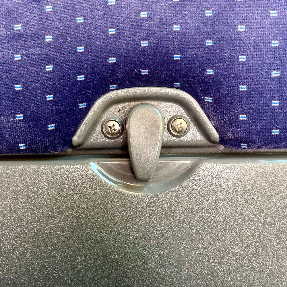Verschluss vom Tisch an der Rückseite vom Zugsitz, das aussieht wie ein Gesicht