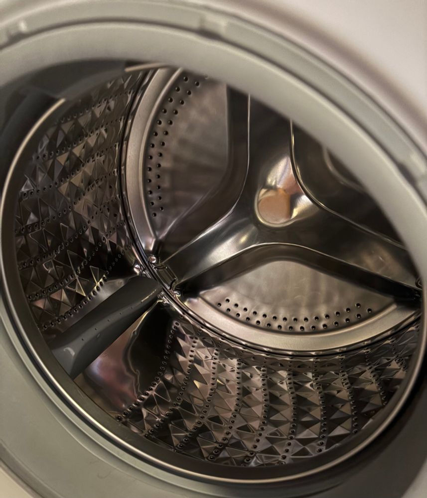 Eine Trommel von einer Waschmaschine. Sie glänzt und ist aus Metall.