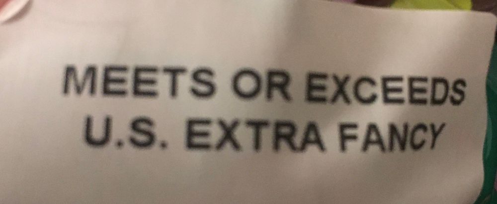 A rumpled, poorly focused white paper label which says "MEETS OR EXCEEDS U.S. EXTRA FANCY"