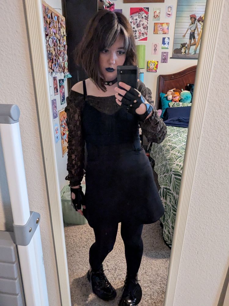 Me in my closet cosplay of Rogue from X-Men Evolution. I am wearing a lace dark green top, black tank top, black skirt, black tights, black docs, a choker, and fingerless black gloves. 