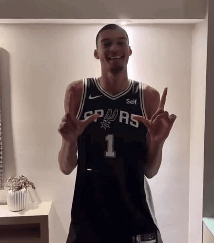 a man is wearing a spurs jersey and giving the peace sign