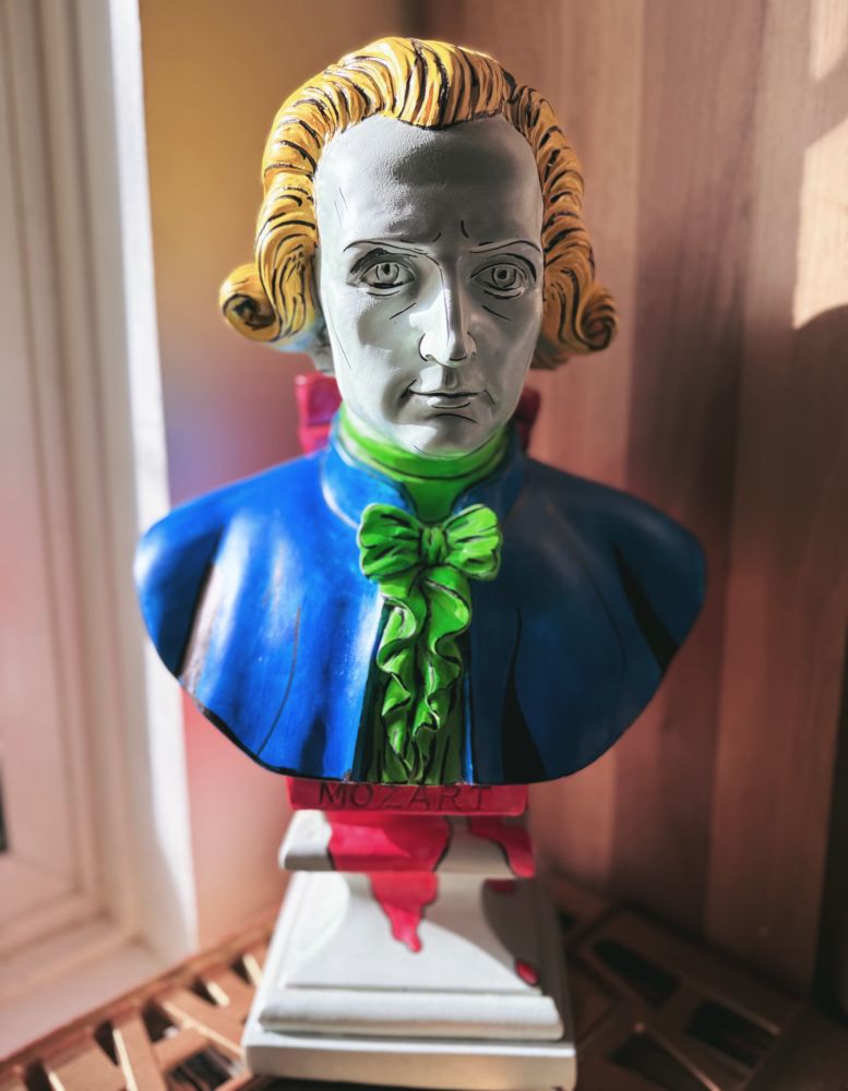 Busy of Mozart, roughly 15 inches tall, painted in bright colours with black outlining details 