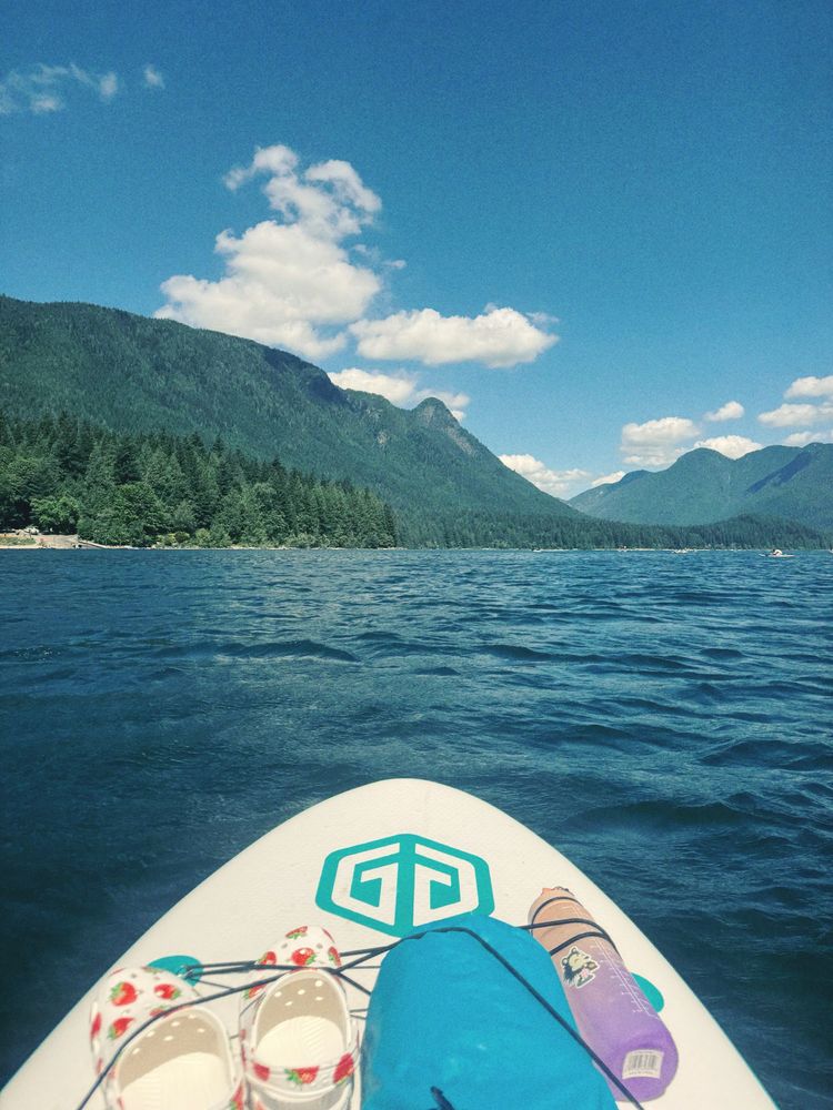 MJ’s point of view, sitting on a paddle board in the middle of the lake with mountains in the distance 