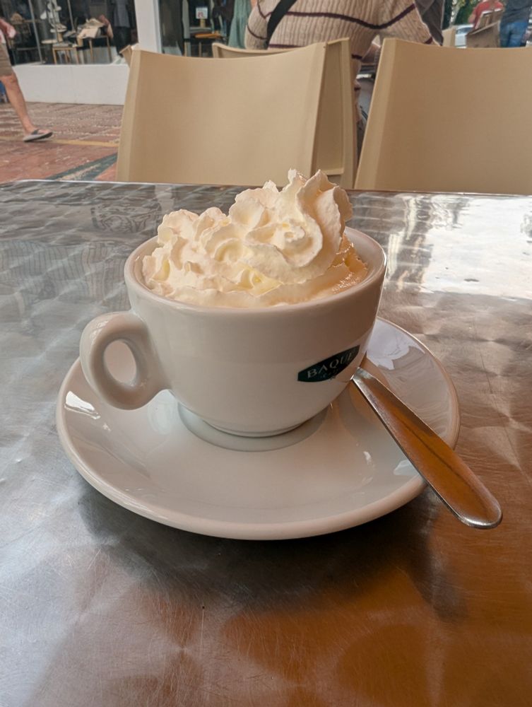A cup of hot chocolate with lots of cream on top