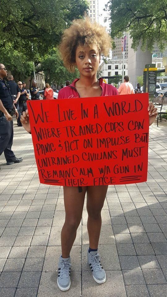 Photo of a young woman holding a sign which reads - 