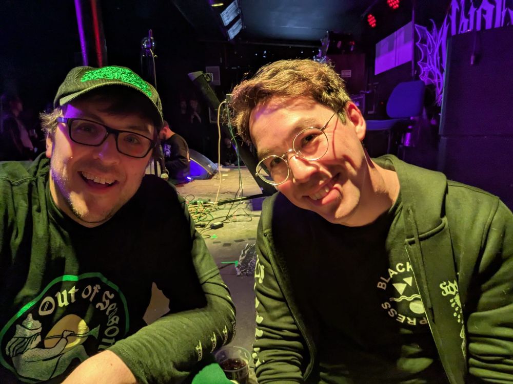 Two men sitting on a stage taking a selfie 
