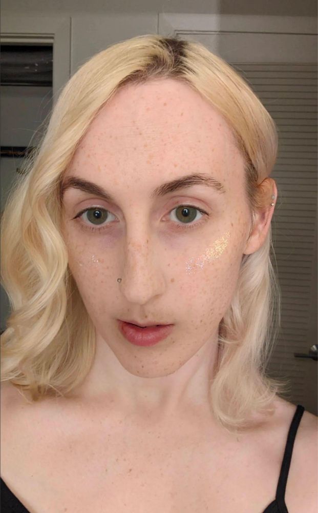 Pale young Caucasian woman with androgynous features, hazel eyes, and shoulder-length bleached blonde hair.