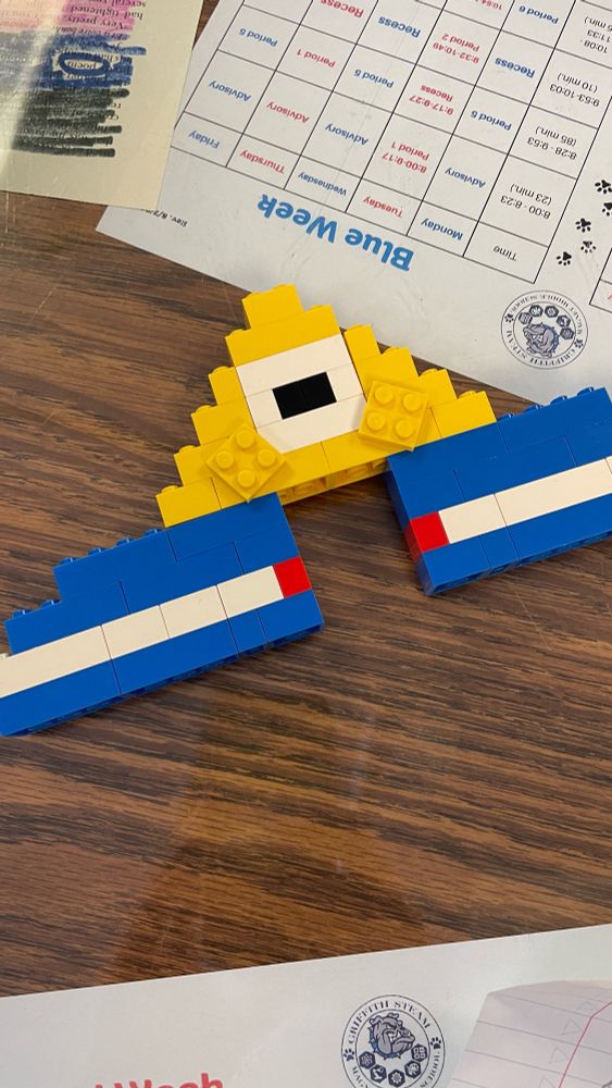 A yellow triangle with a center eye with blue and white feet made from LEGO