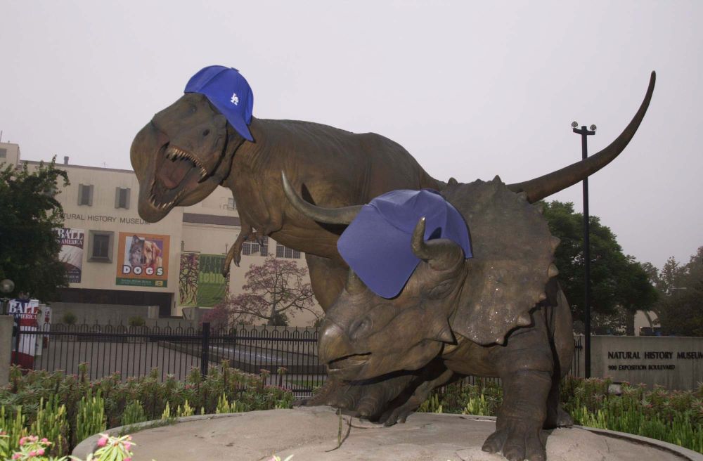 The Natural History Museum of Los Angeles County's exterior "Dueling Dinosaurs" T. rex statue donning a Dodgers baseball cap and t-shirt.