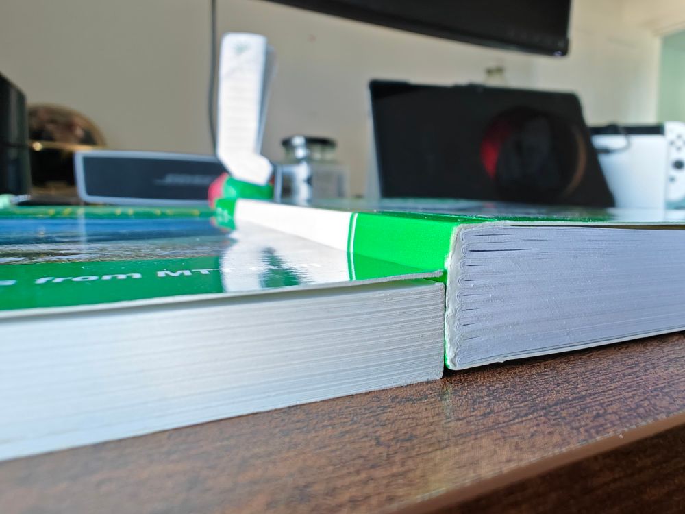 The edge of two green books. The one on the right is about a quarter thicker than the one on the left.