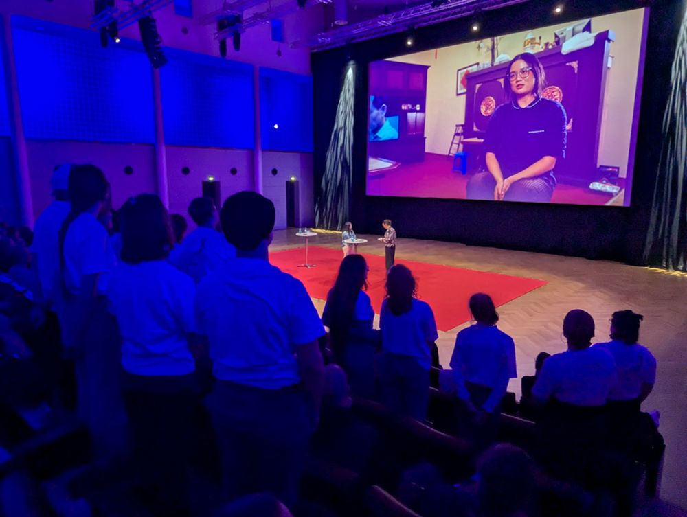 Menschen von hinten, die in einem Saal stehen.