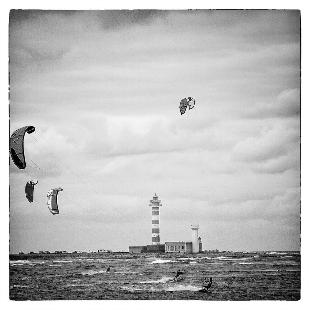 Surfende Menschen vor dem Faro de Tostón