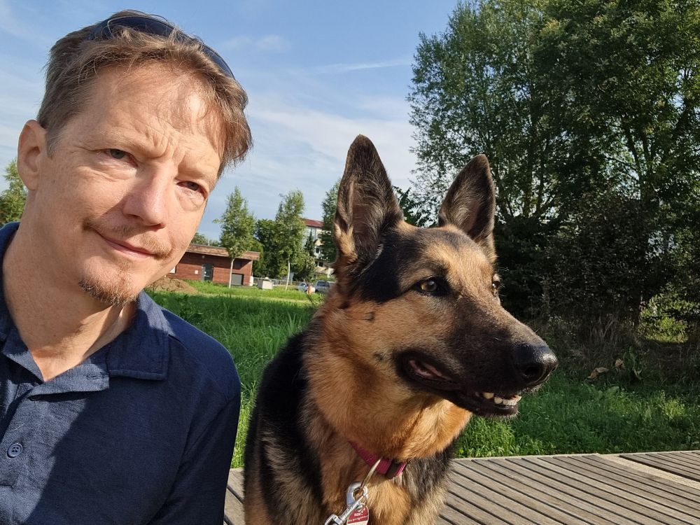 Man and dog sitting next to each other looking into the distance.