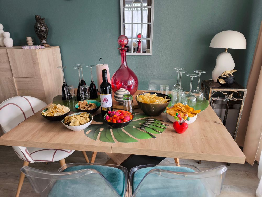 Table du salon avec apéro dinatoire en cours d'installation, verres et déco. Chez moi. 