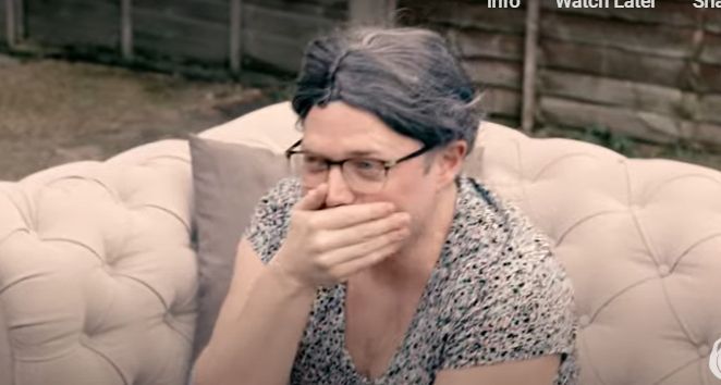 Rob Beckett with a wig and a top, laughing