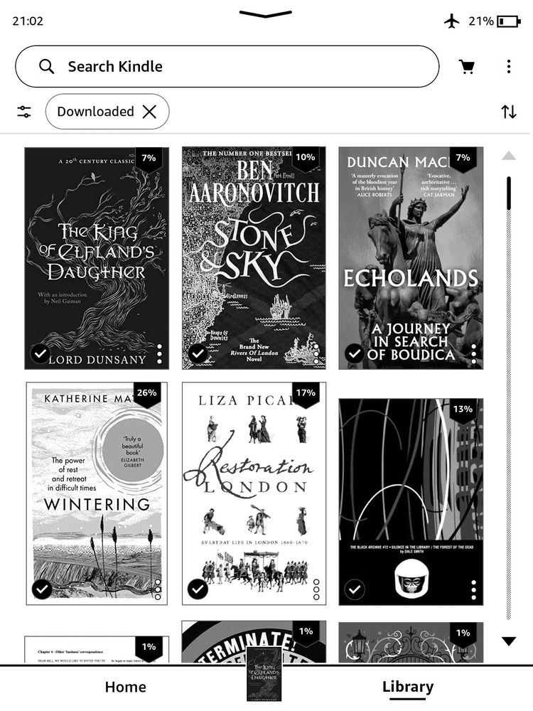 Screenshot of a Kindle Paperwhite e-reader in portrait mode with a black and white screen. The view shows 6 book covers, in 2 rows of 3. At the top are "The King of Elfland's Daughter" by Lord Dunsany, "Stone & Sky" by Ben Aaronovitch, and "Echolands: In Search of Boudica" by Duncan Mackay. Then on the second row are "Wintering" by Katherine May, "Restoration London" by Liza Picard, and "The Black Archive #72: Silence in the Library / Forest of the Dead" by Dale Smith. Each book has a percentage number showing progress so far. Some are further through, e.g. 26% on "Wintering" and 17% for "Restoration London", while others are newer started.