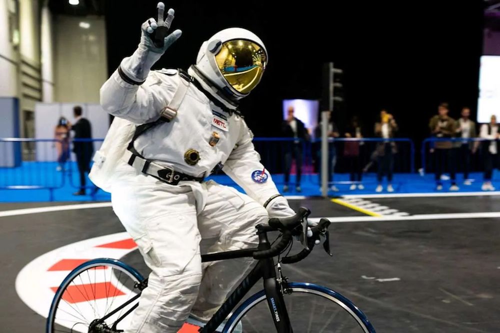 Person wearing a space suit while riding a bike.