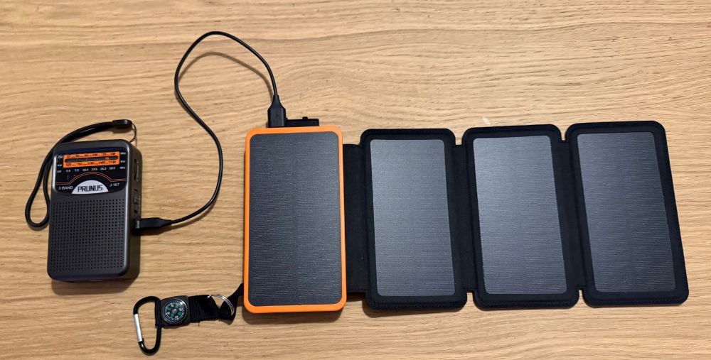 Photo of portable radio and solar battery pack on wooden table