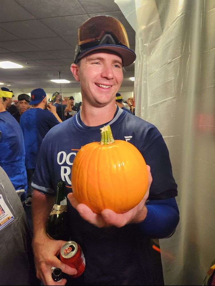 A smiling polar bear holding a pumpkin and two beers.