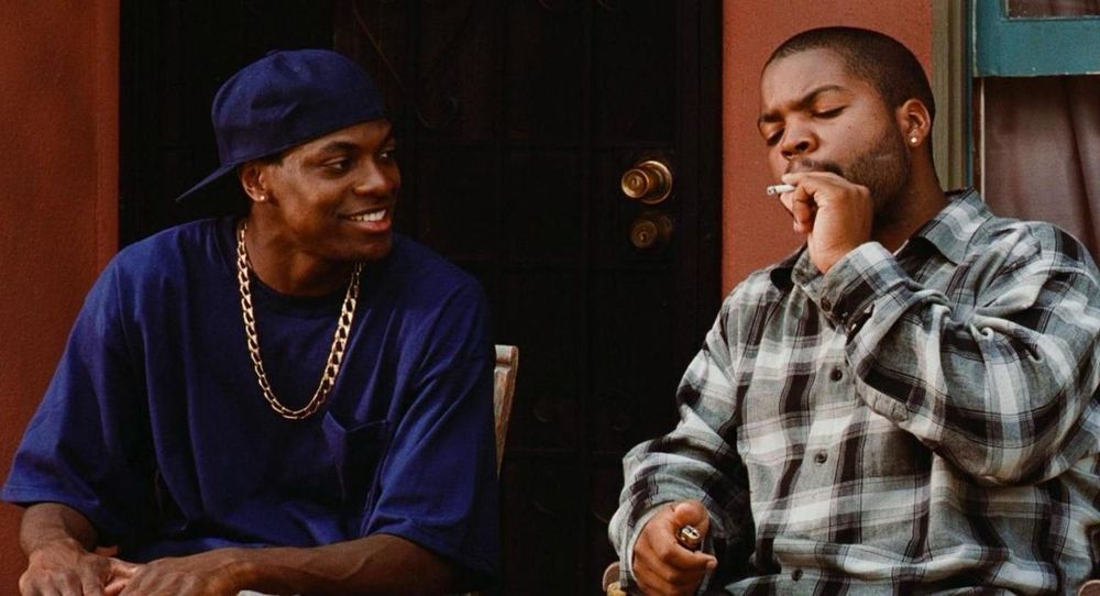 Screen still from the film “Friday” featuring actors Chris Tucker and Ice Cube sharing a joint.