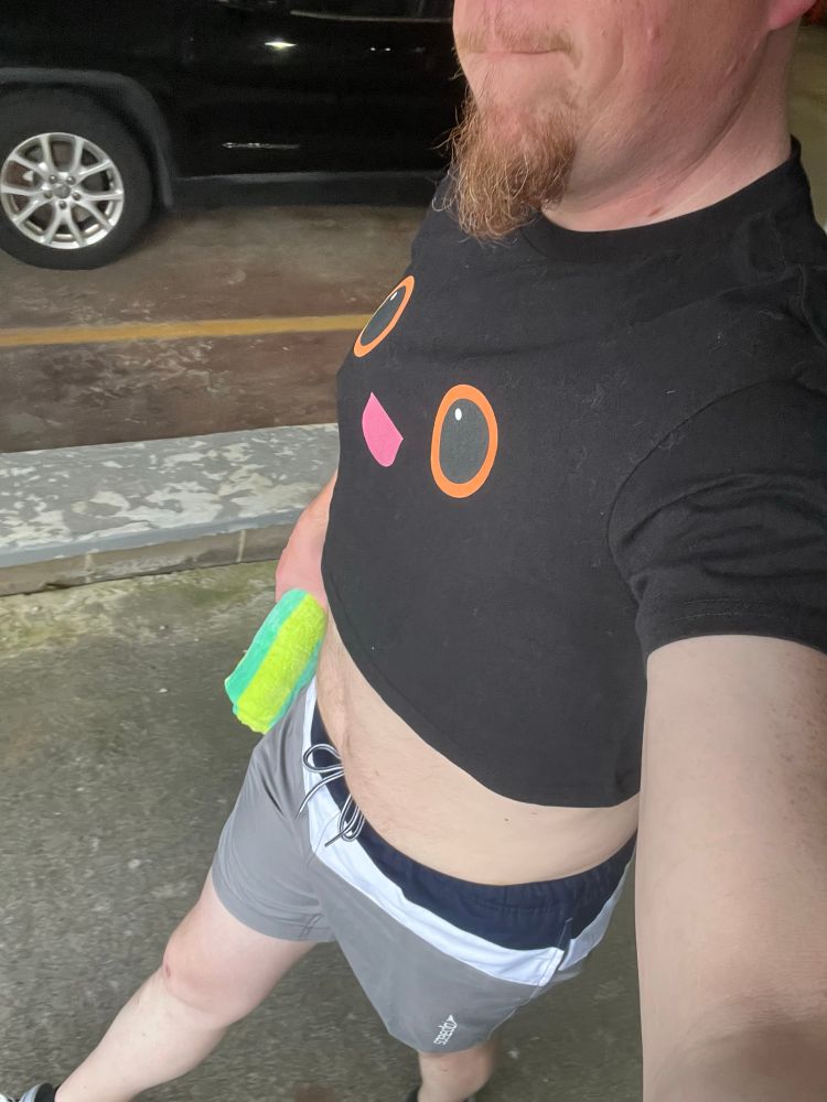 Me, swim trunks, crop top, carrying a rolled up beach towel 