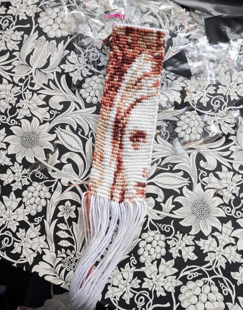 A knotted string bookmark with a pattern of Buffy the Vampire Slayer in shades of white and brown 