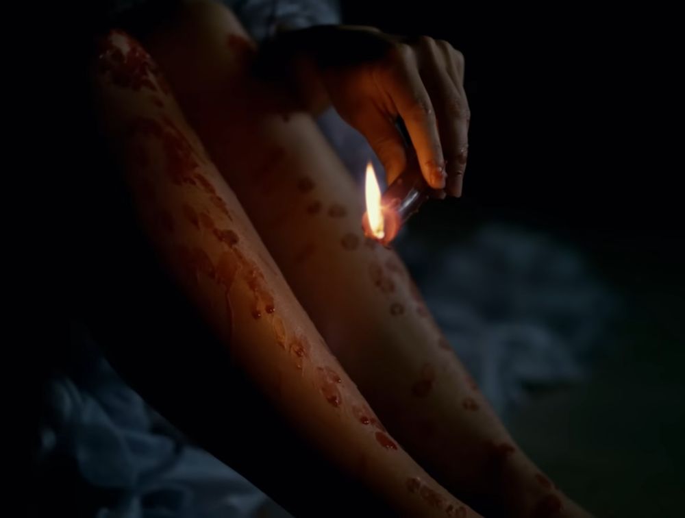 Screenshot from House by Charli xcx with a woman dropping candle wax on her legs