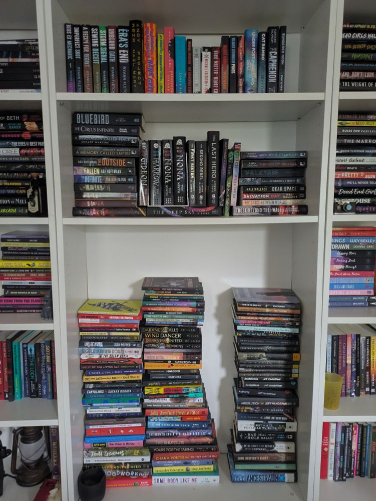 A bookshelf with missing shelves and books stacked on top of each other