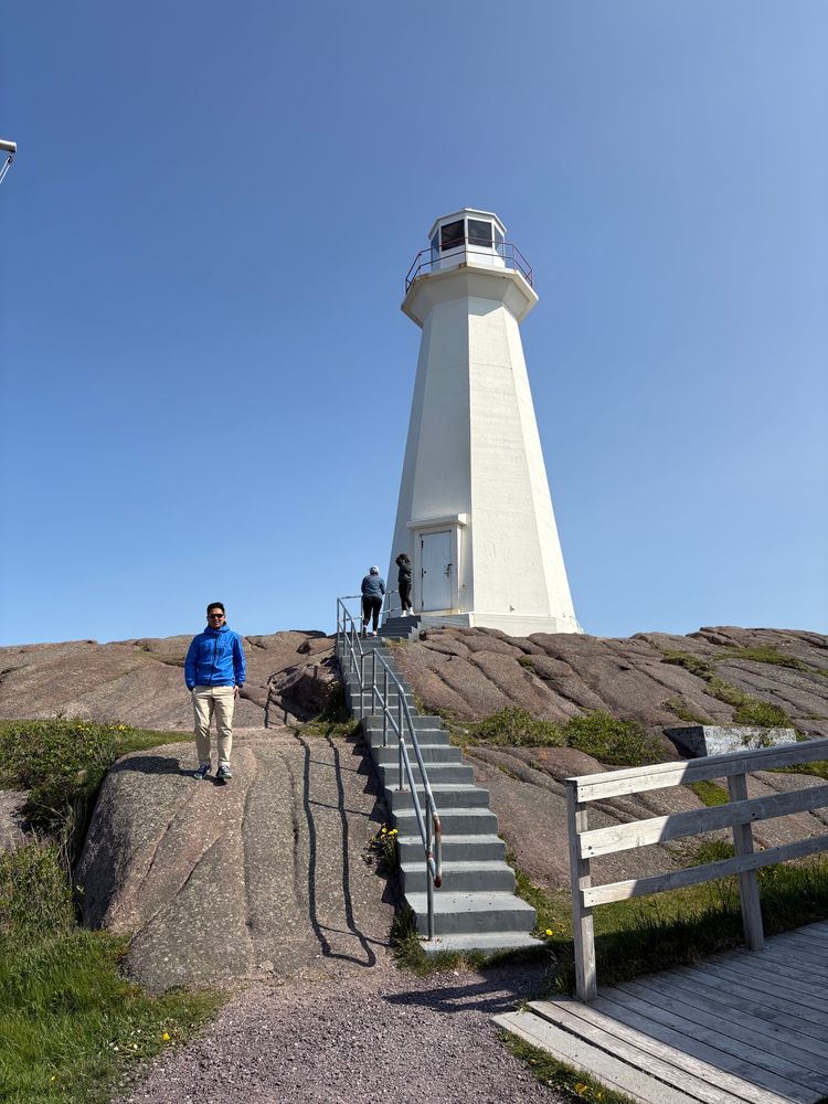 Man in a blue coat standing in front of the lighthouse on North America’s most eastern point, Cape Spear