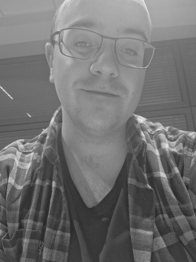 Black-and-white photo of me in a black t-shirt and a plaid shirt.