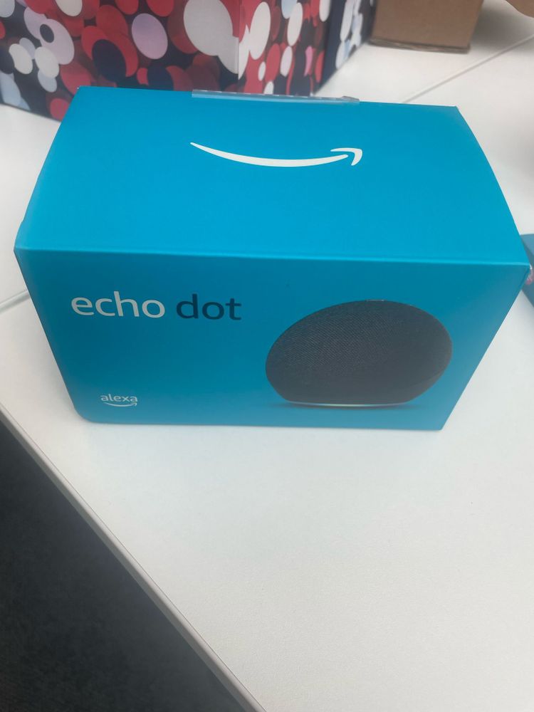 A blue box on a white table. The box says 'echo dot' and shows an image of a circular black echo dot.