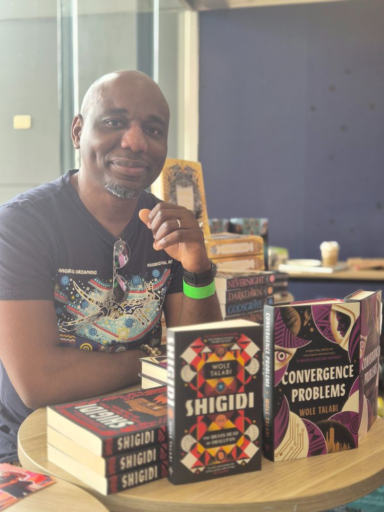 Wole talabi in front of his books  shigidi and convergence problems
